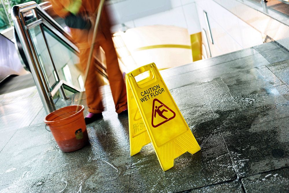 Man washing floor next to caution sign